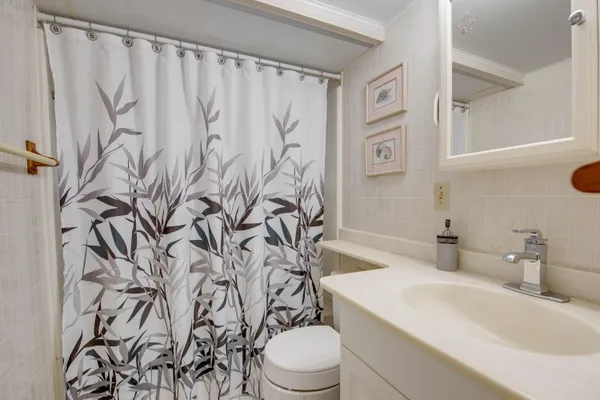 a bathroom with a shower curtain sink and a toilet