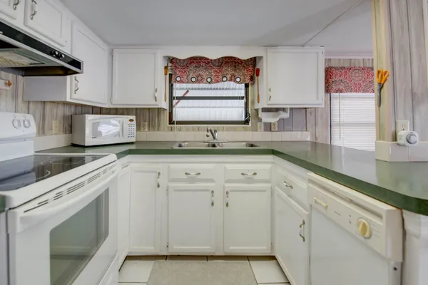 a kitchen with granite countertop white cabinets and white appliances