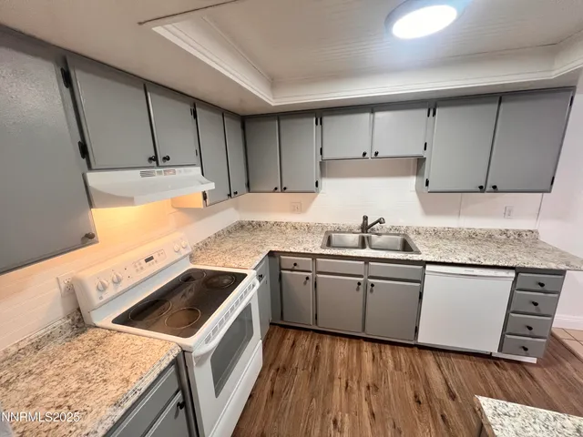 a kitchen with granite countertop a sink a stove and cabinets