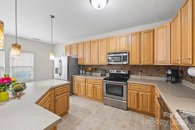 a kitchen with stainless steel appliances granite countertop a stove a sink dishwasher and a refrigerator