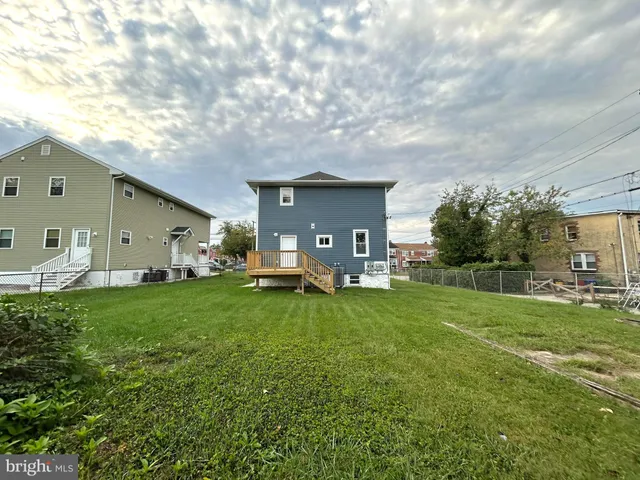 a backyard of a house with table and chairs plants and large tree