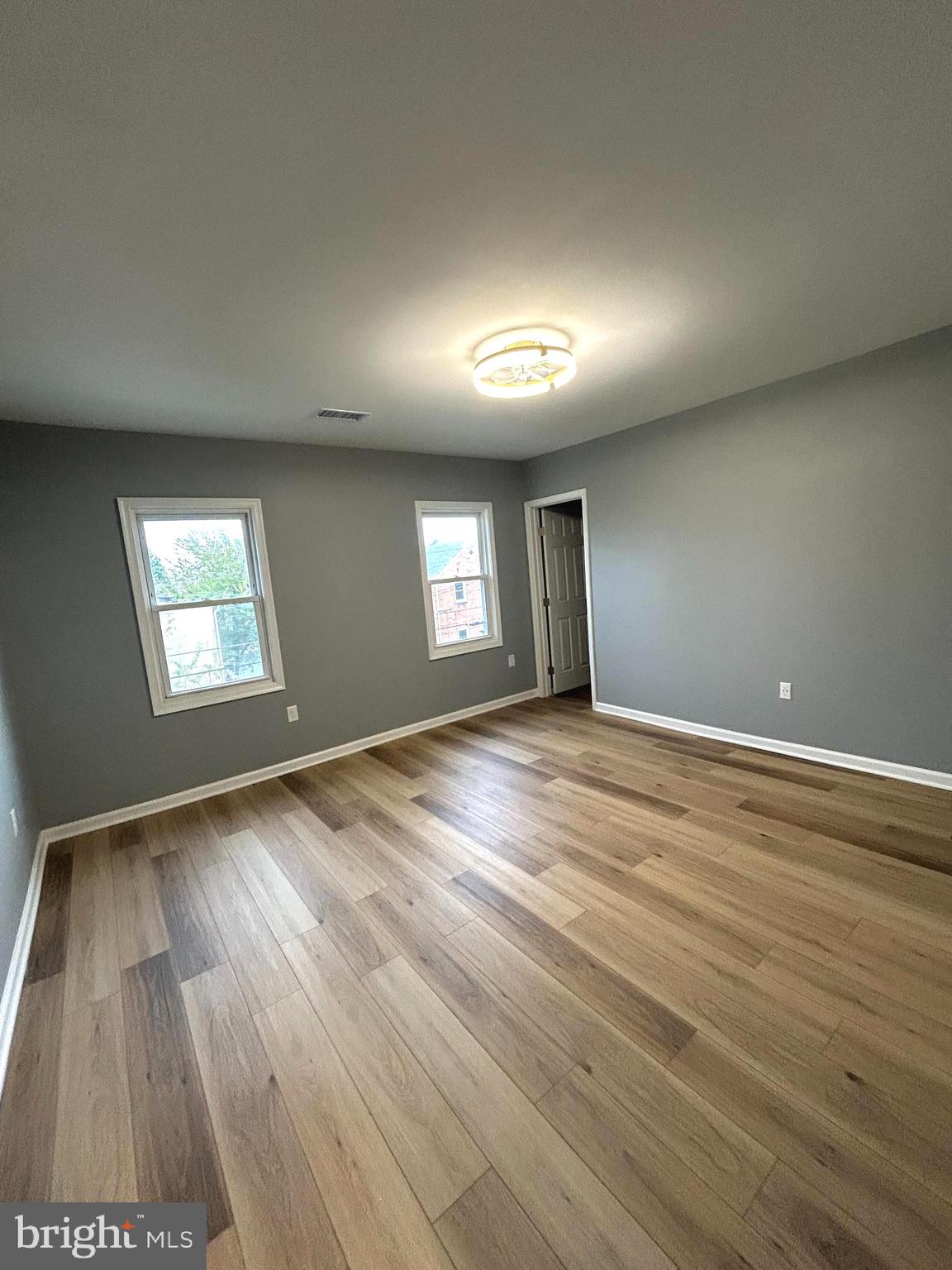 3902 West Rogers Avenue, Unit 2 Baltimore, MD 21215 - Photo 4 of 15 an empty room with wooden floor and windows