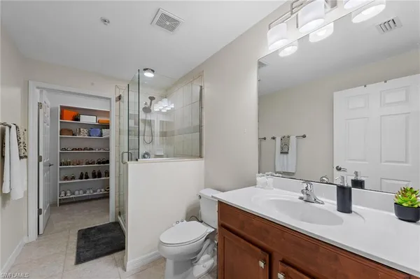 a bathroom with a granite countertop sink a toilet a mirror and shower