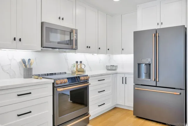 a kitchen with stainless steel appliances white cabinets and a stove a refrigerator with white countertops