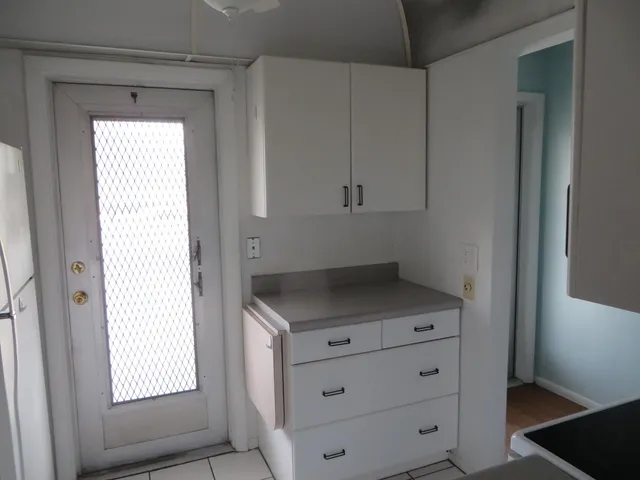 a kitchen with white cabinets and window