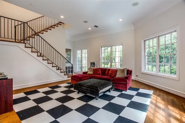 a living room with a black white checkered floor with a gaming machine and dining chairs