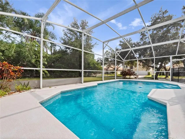 a view of a swimming pool with a yard and wooden fence