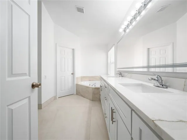 a spacious bathroom with a double vanity sink a toilet and a mirror