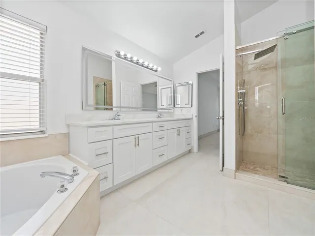 a spacious bathroom with a tub sink shower and mirror