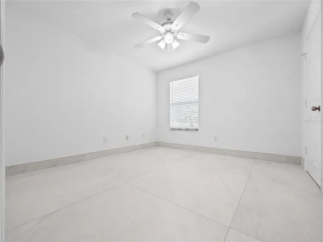 an empty room with windows and ceiling fan
