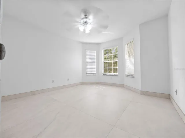 an empty room with windows and fan