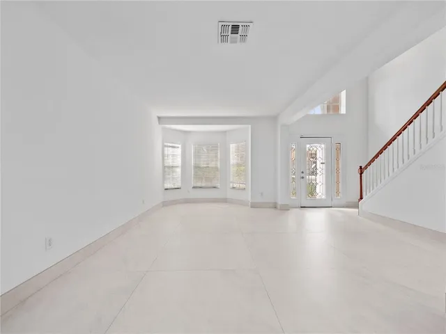 a view of an empty room with wooden floor and stairs