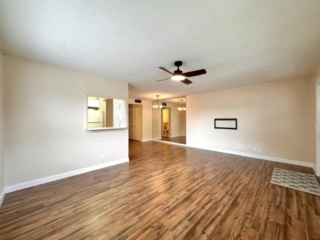 a view of empty room with wooden floor and fan