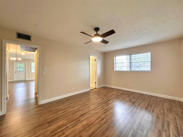a view of an empty room with window and wooden floor