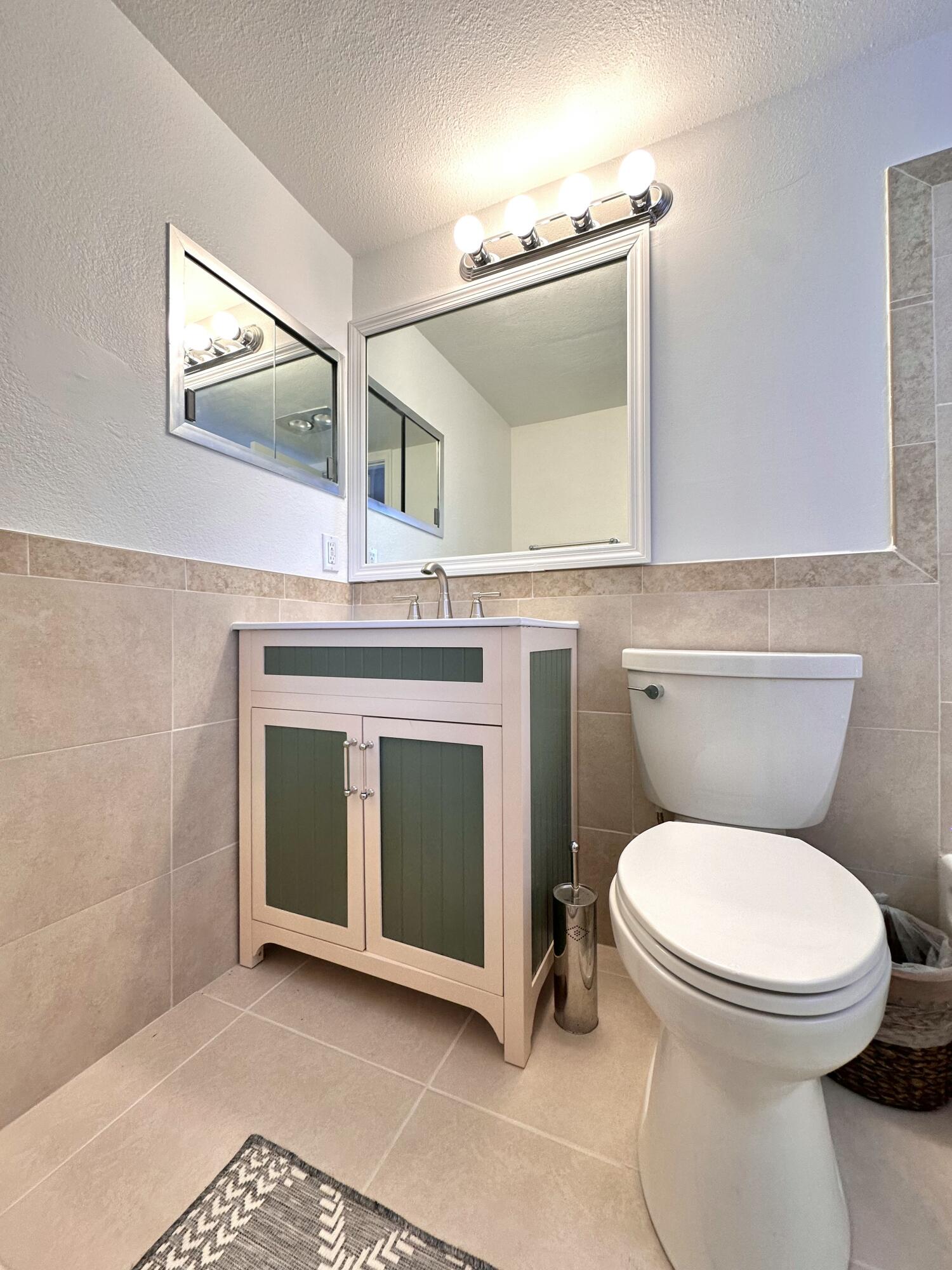 47 Camden B West Palm Beach, FL 33417 - Photo 24 of 36 a bathroom with a toilet a sink and mirror