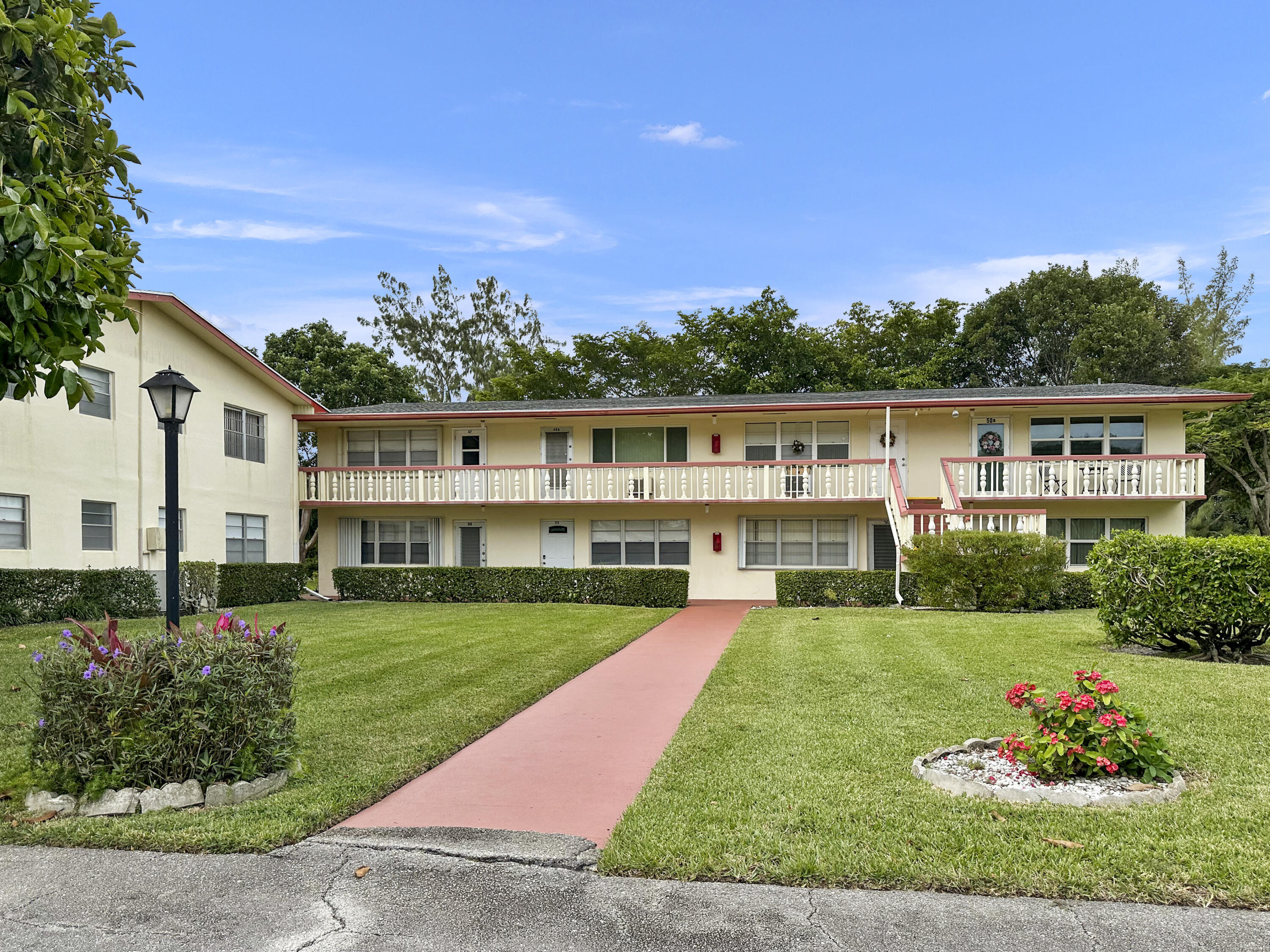 47 Camden B West Palm Beach, FL 33417 - Photo 5 of 36 a view of a white house with a big yard and potted plants