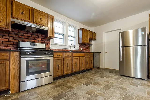 a kitchen with stainless steel appliances granite countertop a stove a refrigerator and a stove top oven