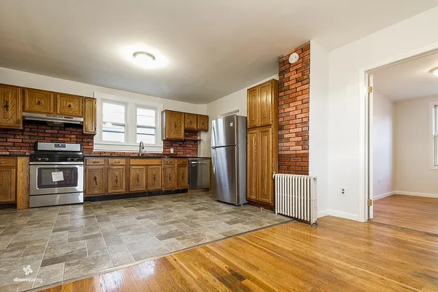 a kitchen with stainless steel appliances granite countertop a refrigerator oven a sink dishwasher and white cabinets with wooden floor