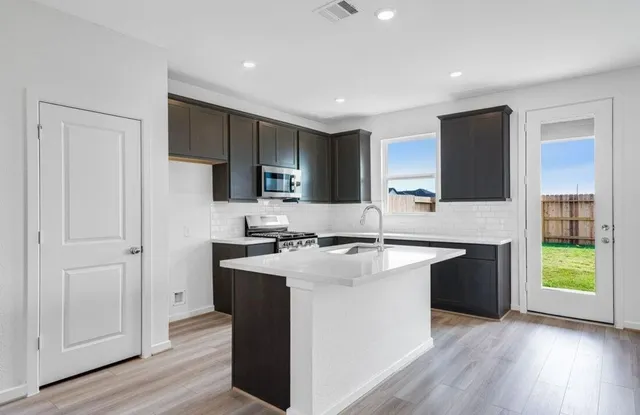 a kitchen with stainless steel appliances granite countertop a sink stove and refrigerator