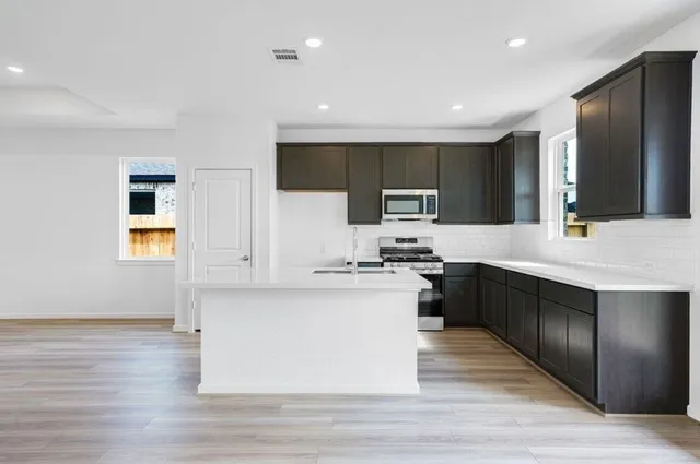 a large kitchen with a large counter top stainless steel appliances and cabinets