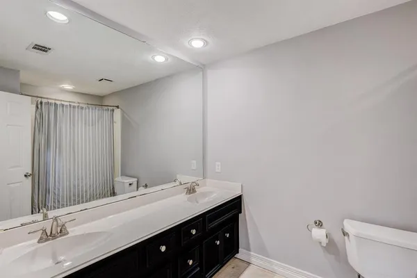 a bathroom with a double vanity sink toilet and a mirror