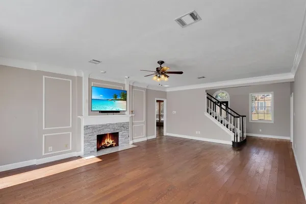 a view of an empty room with wooden floor fireplace and a window