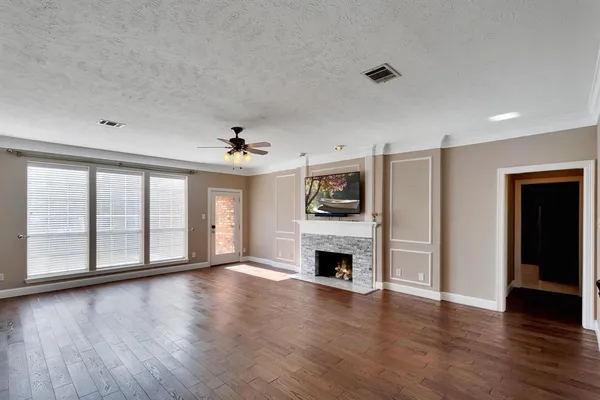 an empty room with wooden floor fireplace and windows