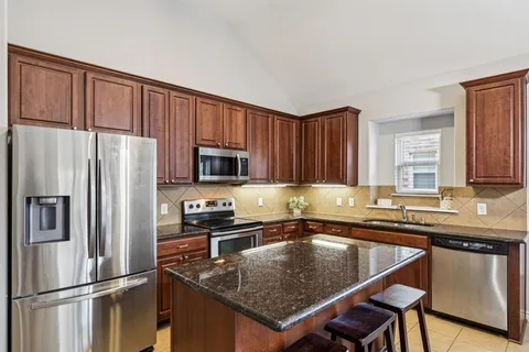 a kitchen with stainless steel appliances granite countertop a refrigerator a sink a stove a microwave and center island