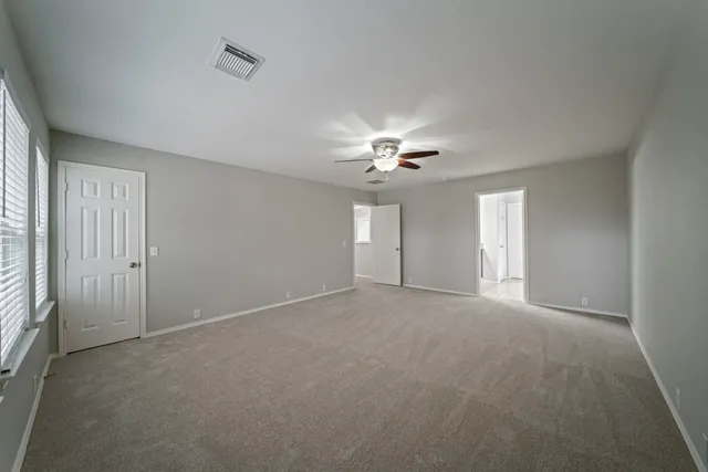 a view of an empty room with a chandelier fan