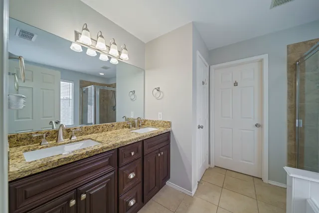 a spacious bathroom with a granite countertop sink a mirror and a shower