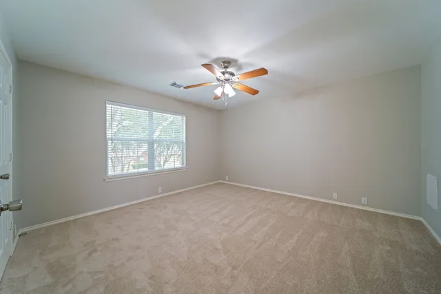 an empty room with a window and a fan