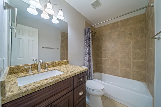 a bathroom with a granite countertop sink a toilet a mirror a bathtub and shower