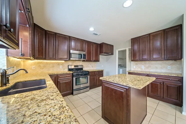 a kitchen with stainless steel appliances granite countertop wooden cabinets sink stove and refrigerator