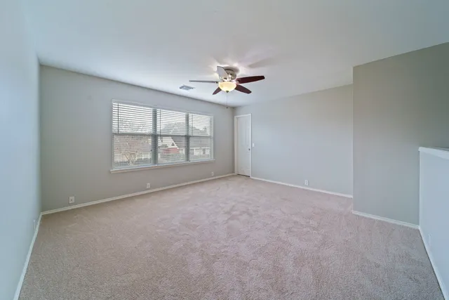 an empty room with windows and ceiling fan