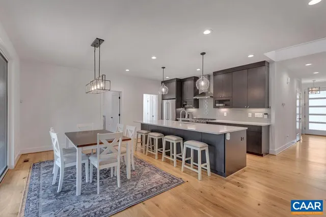 a kitchen with stainless steel appliances kitchen island granite countertop a table chairs sink and cabinets