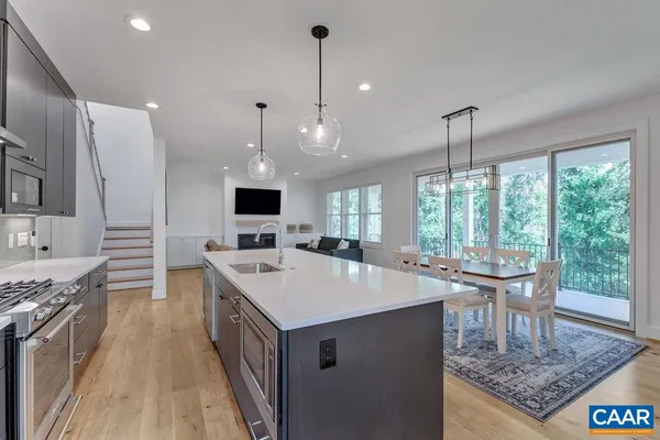 a kitchen with a stove a sink dishwasher and a dining table with wooden floor