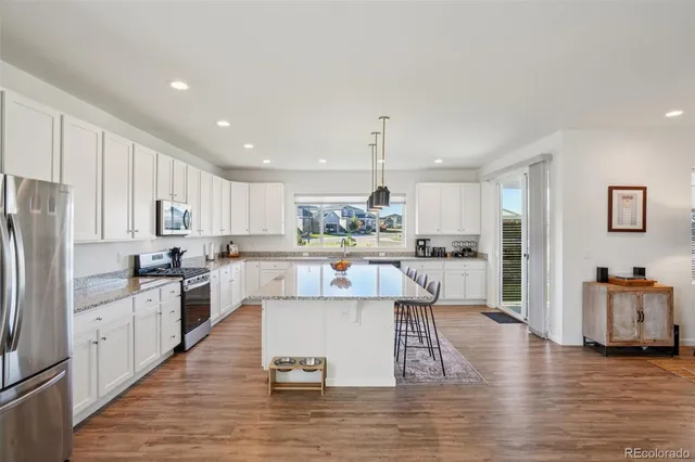 a kitchen with stainless steel appliances granite countertop a refrigerator and a stove top oven