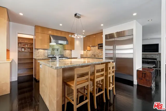 a kitchen with kitchen island granite countertop wooden floor and stainless steel appliances