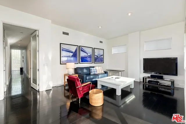 a living room with furniture a flat screen tv and floor to ceiling window