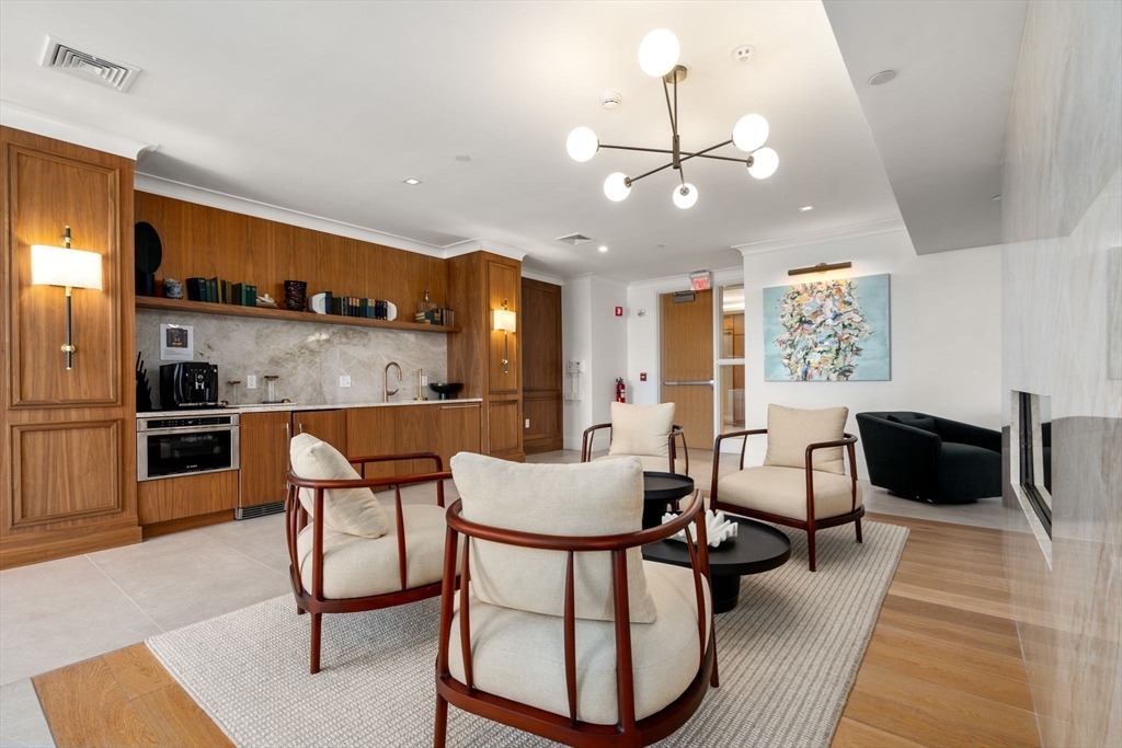 191 Washington Street, Unit 615 Boston, MA 02135 - Photo 14 of 23 a kitchen with stainless steel appliances kitchen island granite countertop a stove a sink a dining table and chairs with wooden floor
