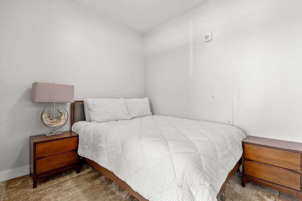 191 Washington Street, Unit 615 Boston, MA 02135 - Photo 5 of 23 a bedroom with a bed and a lamp on table