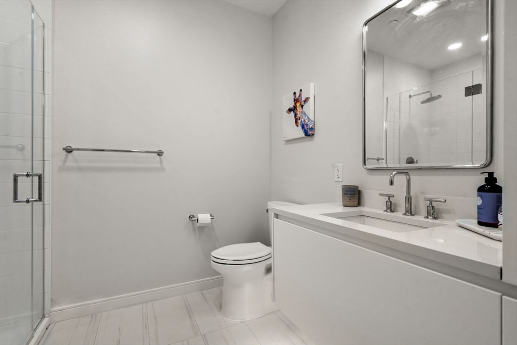 191 Washington Street, Unit 615 Boston, MA 02135 - Photo 7 of 23 a bathroom with a granite countertop sink a toilet and a mirror