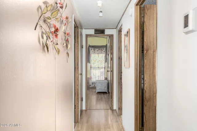a view of a hallway with wooden floor and a bathroom
