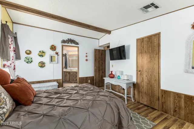a bedroom with a bed and a flat tv screen on the dresser