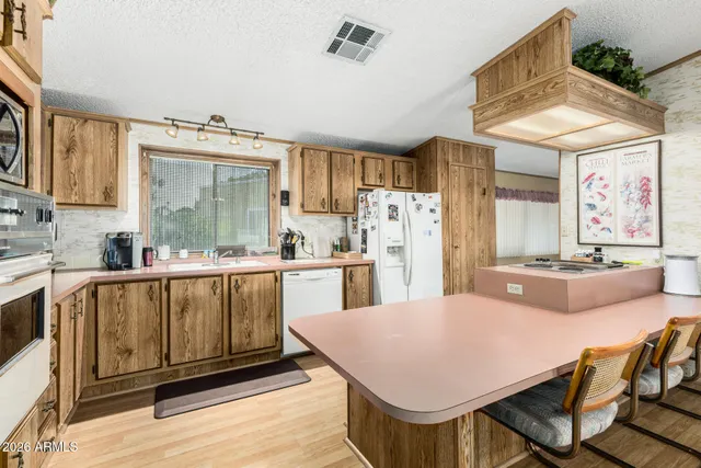 a kitchen with stainless steel appliances kitchen island granite countertop a table chairs in it and a microwave