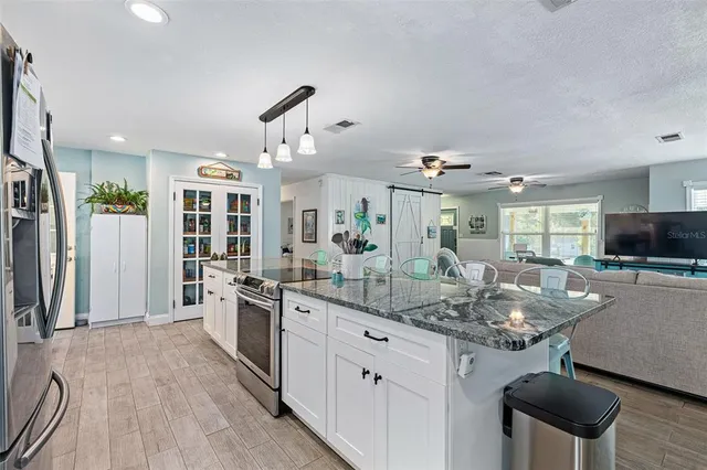 a kitchen with kitchen island granite countertop a sink and refrigerator