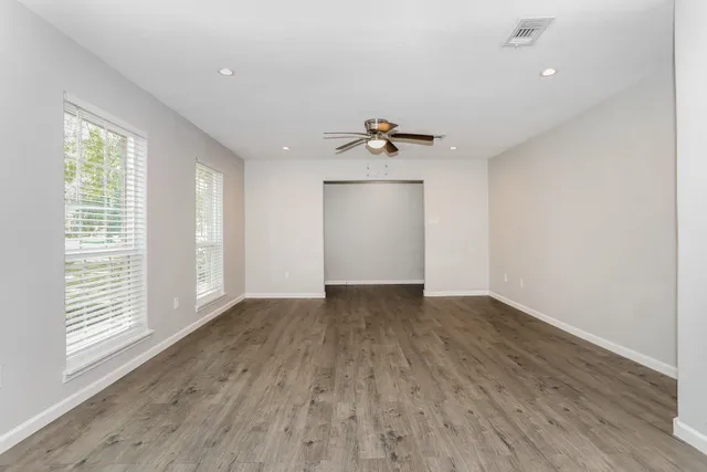 a view of an empty room with a window and wooden floor