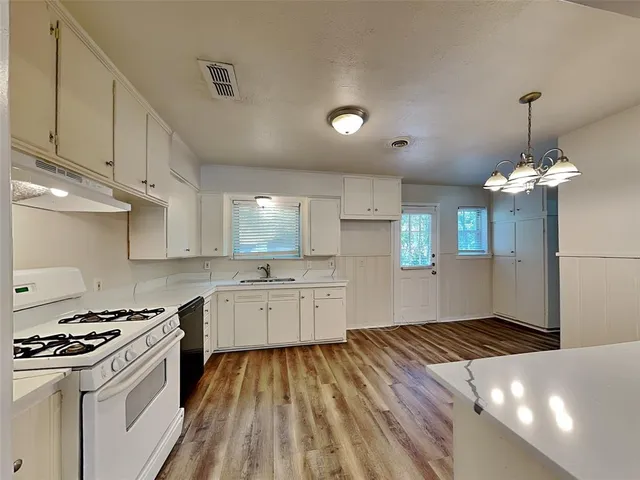 a kitchen with granite countertop a stove a sink dishwasher and a refrigerator