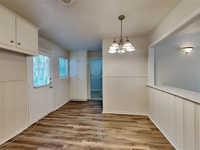 a view of a chandelier in an empty room with window and wooden floor