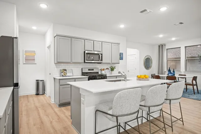 a view of kitchen with stainless steel appliances granite countertop a stove a sink a refrigerator dining table and chairs